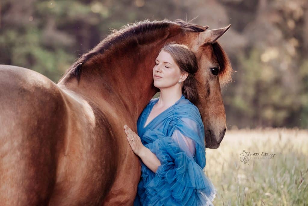 Eine Frau im blauen Kleid mit einem braunen Pferd