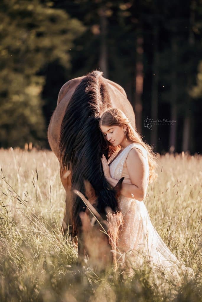 Eine Frau in einem weißen Kleid mit einem braunen Pferd