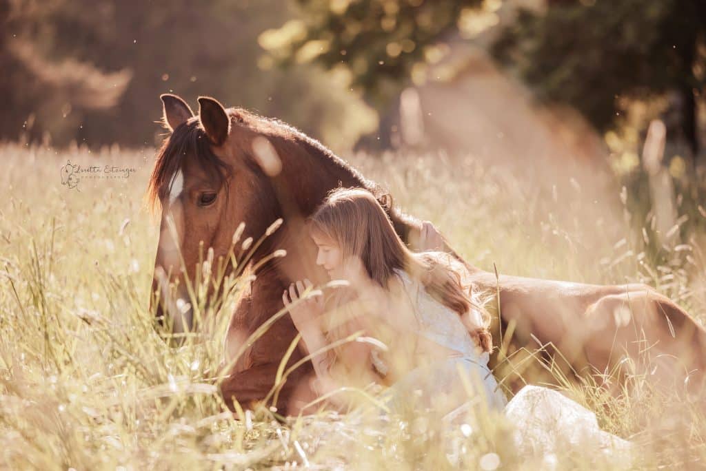 Eine Frau im weißen Kleid mit einem braunen Pferd