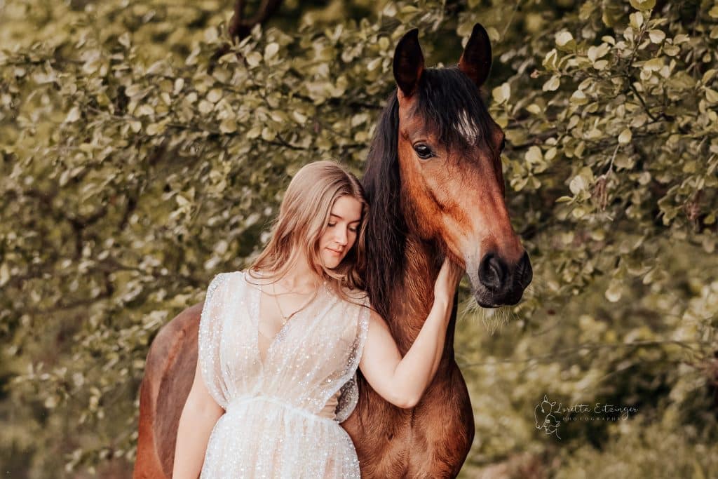 Eine Frau im weißen Kleid mit einem braunen Pferd