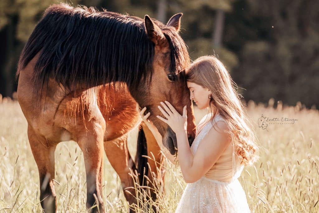 Eine Frau im weißen Kleid mit einem braunen Pferd