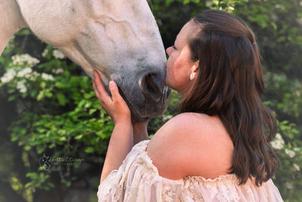 Eine Frau küsst dem Pferd auf die Nase